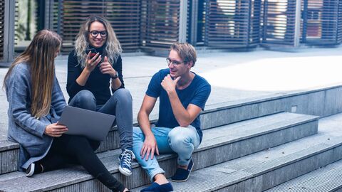Duales Studium IT Hessen Informatik Drei Personen sitzen draußen auf einer Treppe.