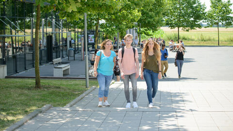 Studenten laufen am Unigebäude vorbei.